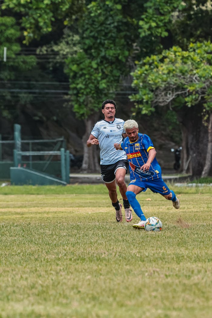 Two male soccer players in action during an intense match on a grassy field outdoors.